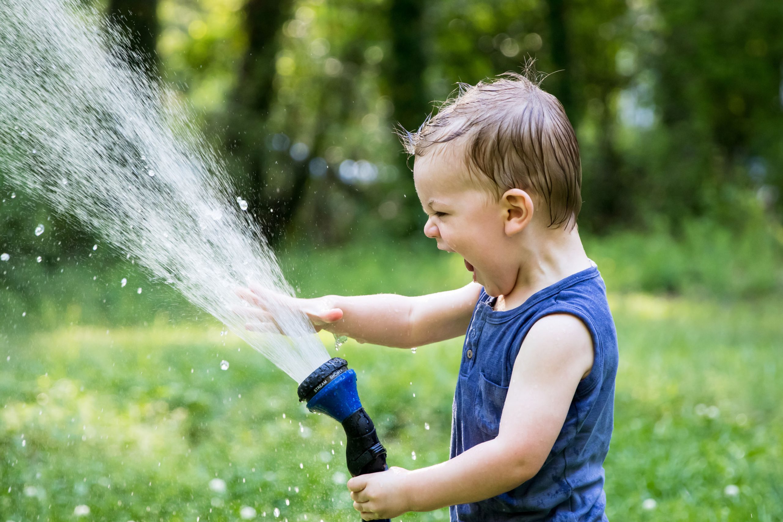 Young boy playing with hose outdoors