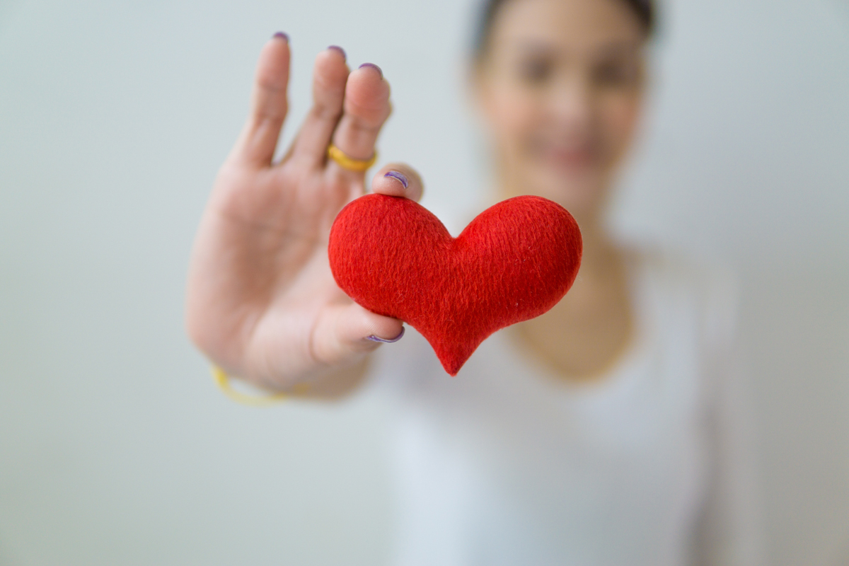 Close up of small red felt heart, held by woman
