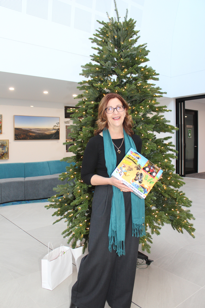 Council's General Manager poses with present and giving tree inside Civic Centre