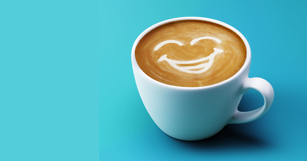 Coffee cup with smiley face in foam on blue background