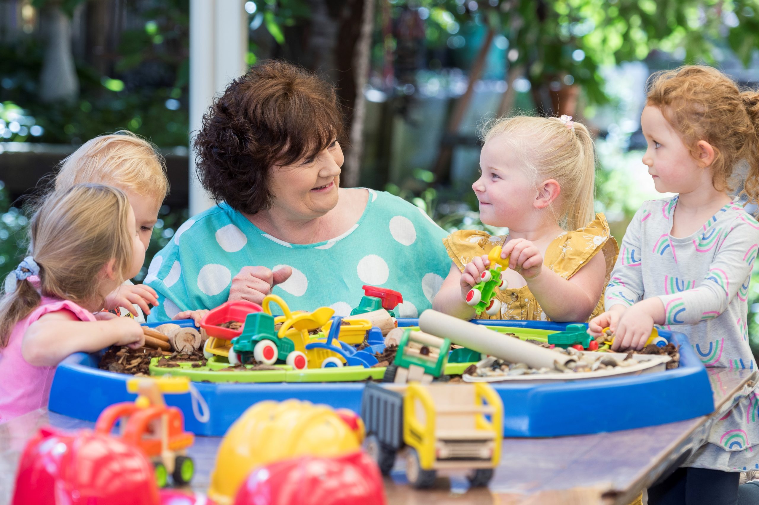 Lady with 4 young children around her doing an activity on a table