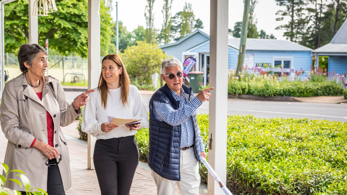 Council staff member walking along a street talking to two residents
