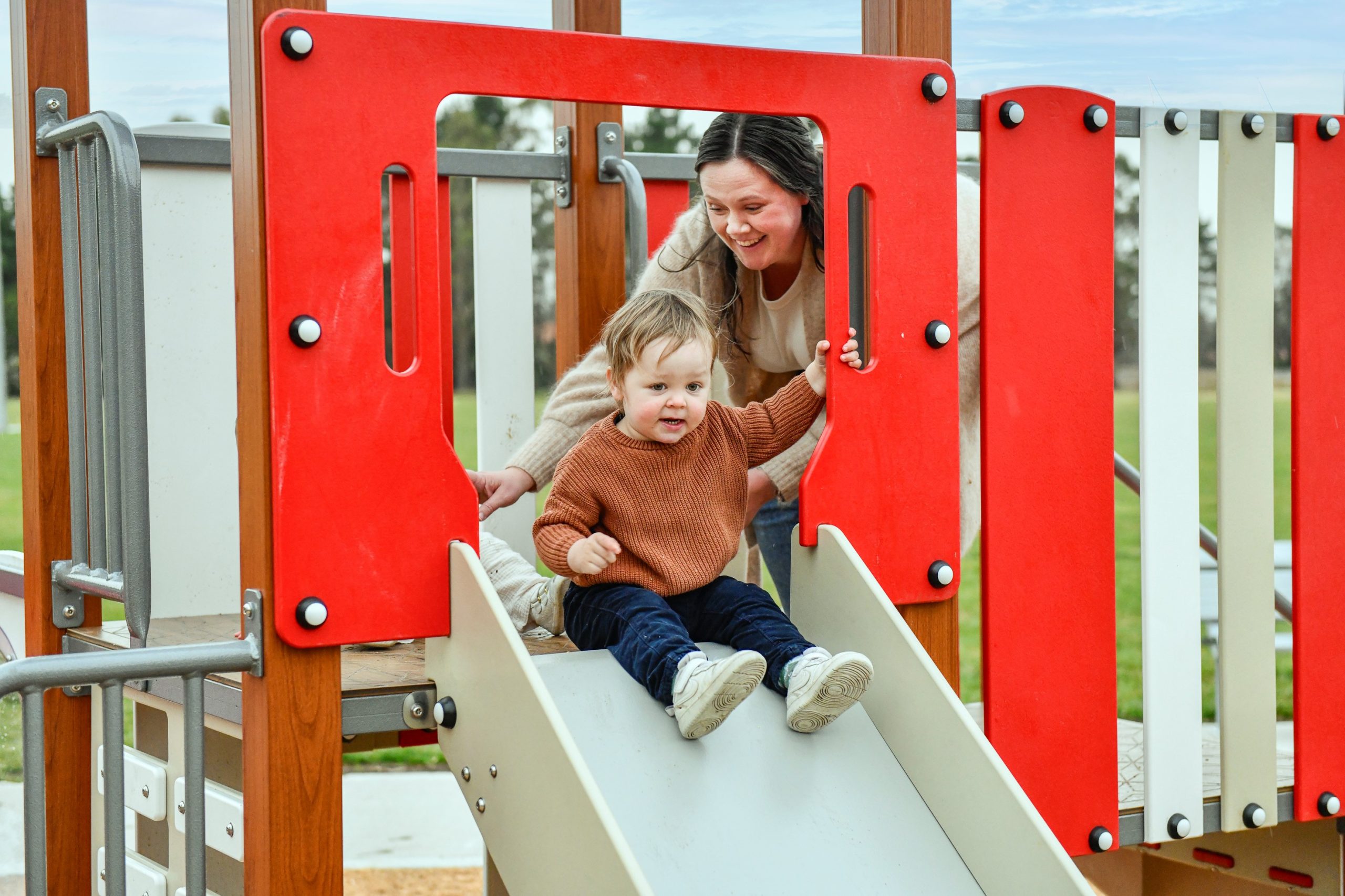 Lady playing with her toddler on the play equipment