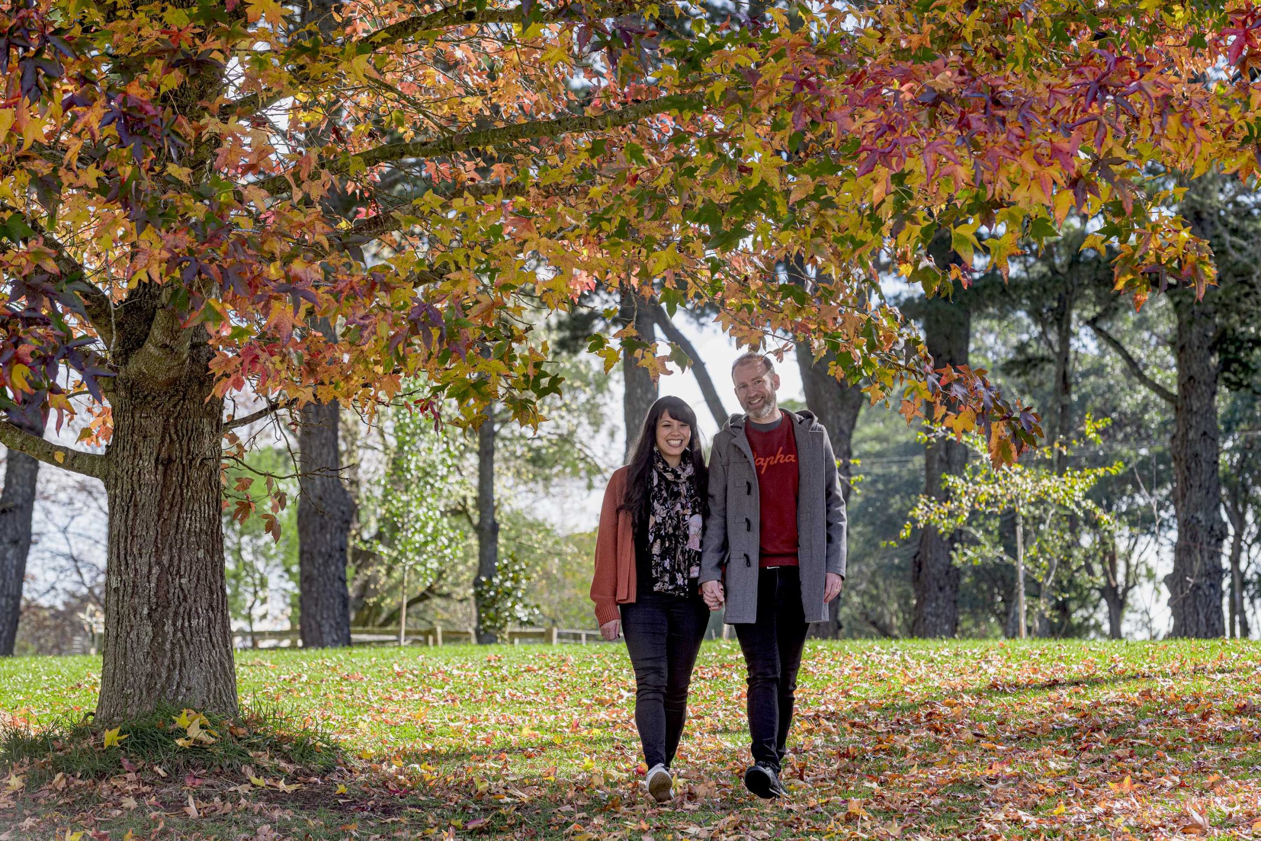two people standing under an autumn tree