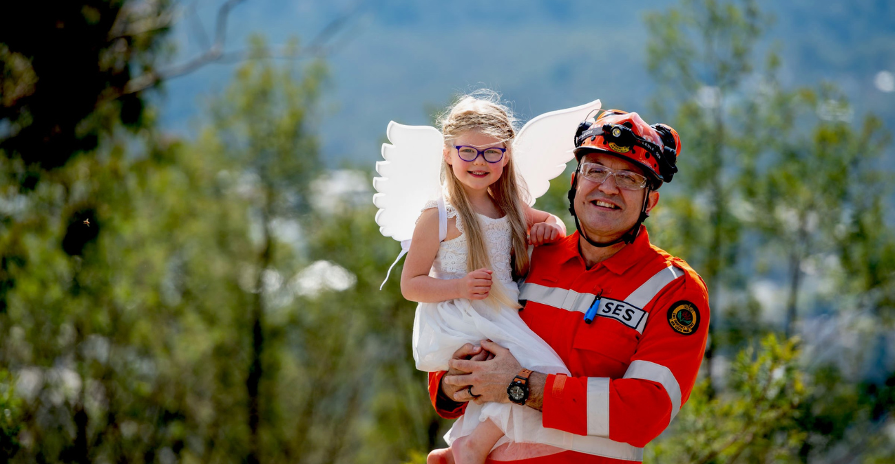 Man in SES uniform carrying young girl dressed as an angel