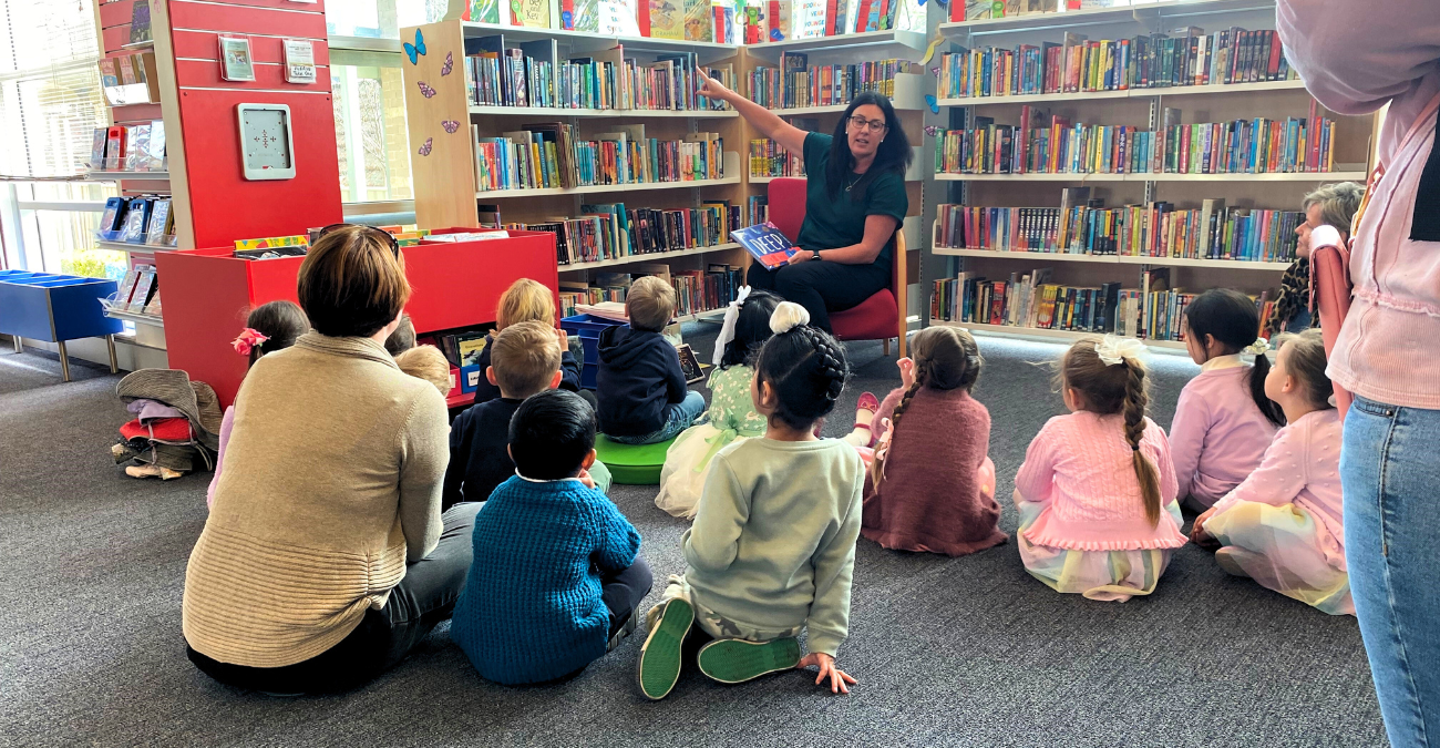 Librarian reading to a class of school kids in the library